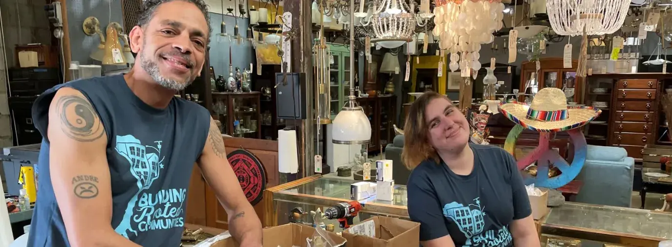 Two Community Forklift employees standing at the register and smiling at the camera.